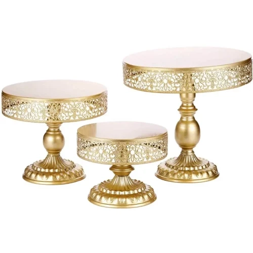 A set of three gold cake stands with white tops.