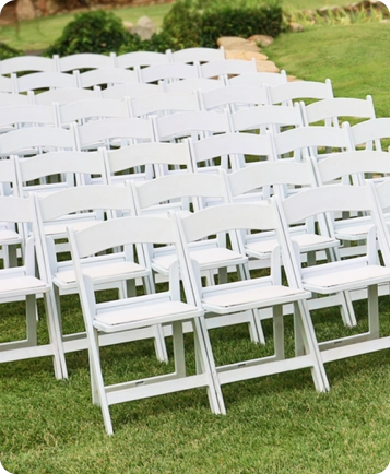 A large group of white chairs in the grass.