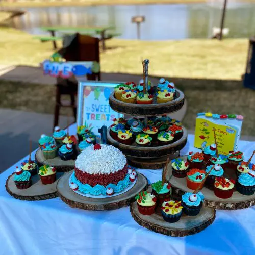 A table with several cakes and cupcakes on it.