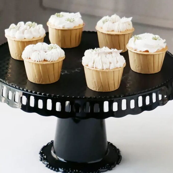 Cupcakes with white frosting on a black cake stand.